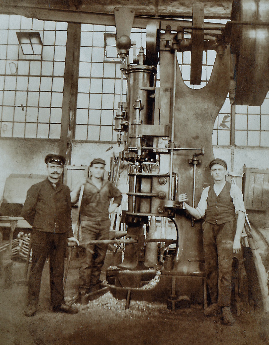 Old picture of three AERZEN employees in front of an AERZEN unit