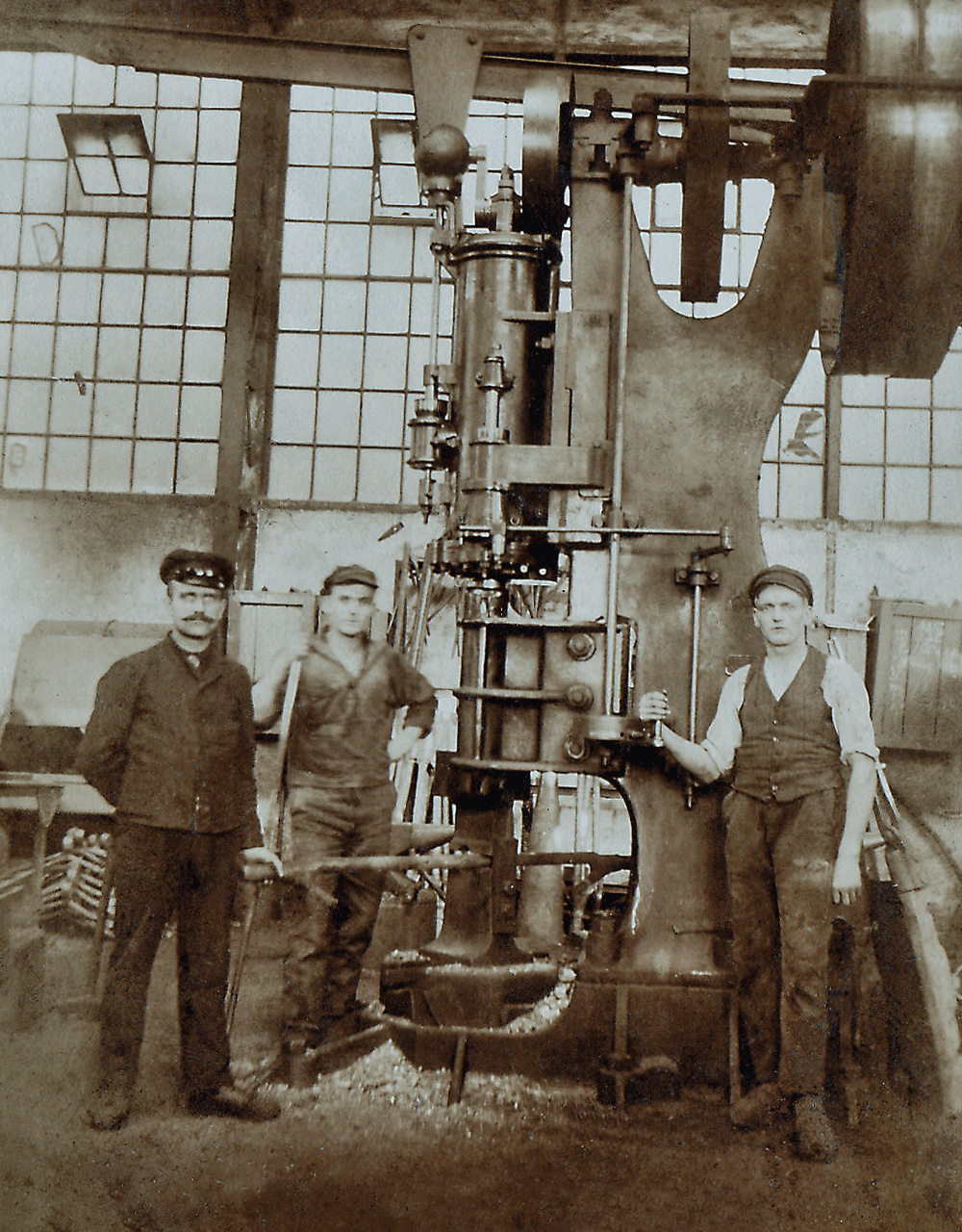 Antiga fotografia de três colaboradores da AERZEN à frente de uma unidade AERZEN